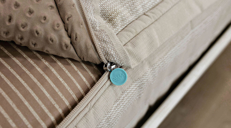Davis-style (tan with white vertical stripes) zipper bedding partially unzipped to reveal the bottom layer sheet and very zoomed in on the zipper.
