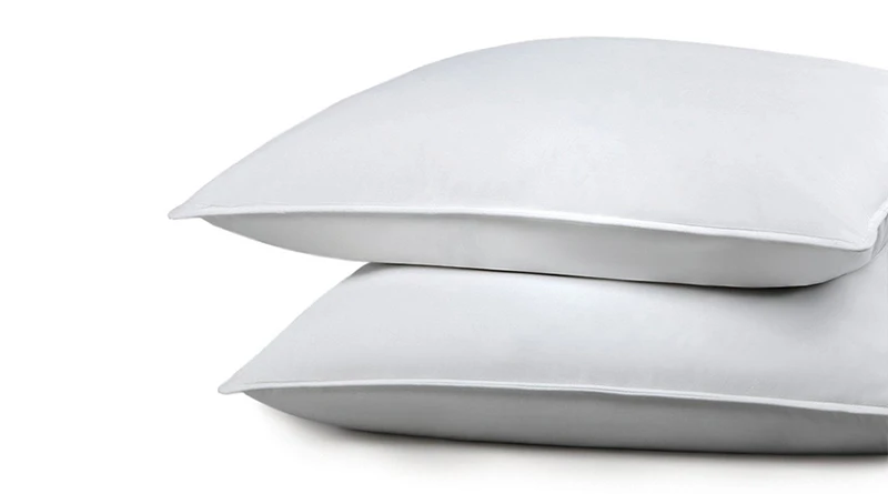 Two white undressed Chamber Down Pillows from Standard Textile Home on a white background set to and slightly cut off on the right side of the frame.