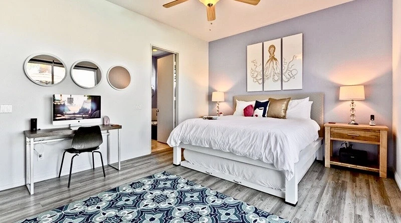 A white king size metal Platform Bed with a trundle underneath and beige headboard in a gorgeous bedroom inside a vacation rental property located in the Coachella Valley in California.