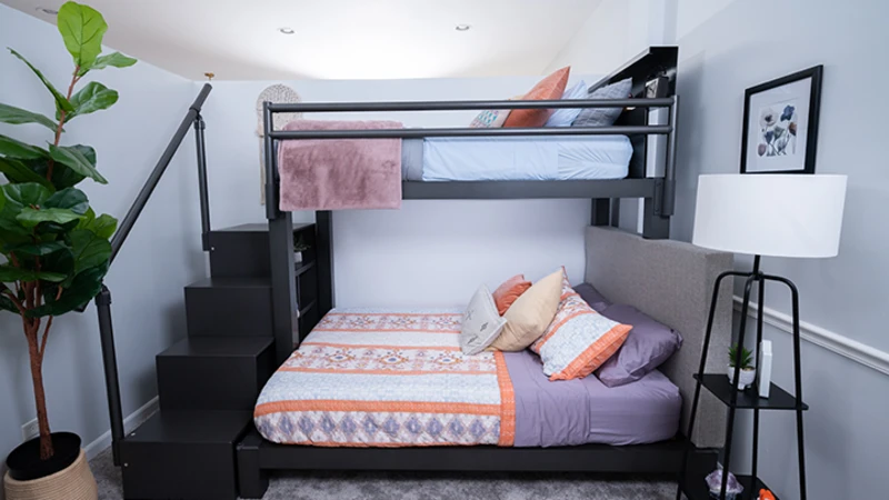 Charcoal Adult Bunk Bed with orange and purple designer bedding and a wooden storage staircase seen in a nice bedroom directly from the left-hand side of the bed frame.