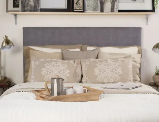 A front angle shot of a queen size Standard Bed from Francis Lofts & Bunks. There is a tray with a coffee pot and two mugs on the bed. It has a gray upholstered fabric headboard.