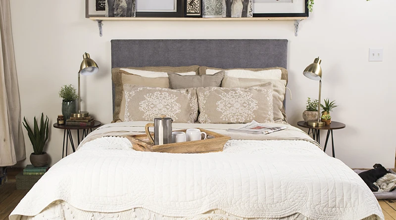 A white Queen size metal Platform Bed with a dark gray headboard and a tray with a coffee pot and cups on the mattress seen directly from the foot of the bed.