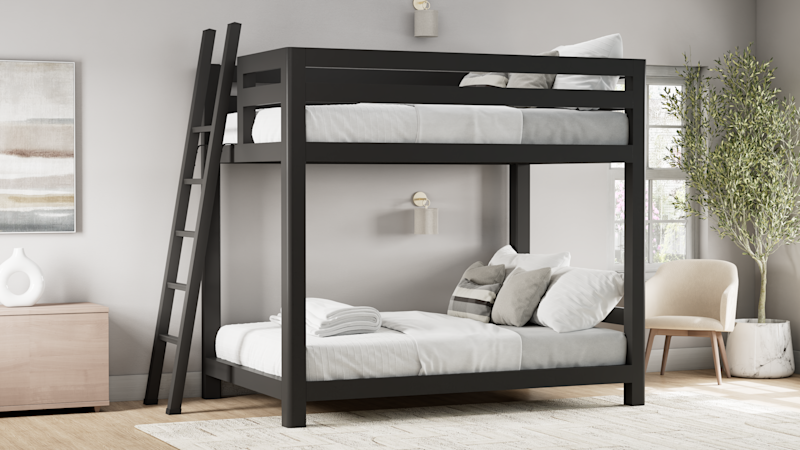 Charcoal queen over queen size Signature Bunk Bed for Adults in a nice, airy, upscale guest room. Has white and light gray bedding on it. Seen from the front and left-hand side of the bed.