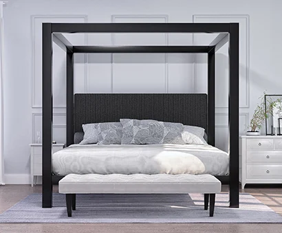 A charcoal Wyoming King size Canopy Bed in a light, sparsely decorated but upscale bedroom. Seen directly from the foot of the bed.