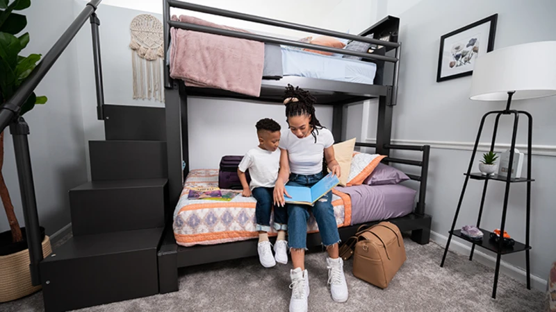 Young mother and her young son sitting on the bottom bunk of a charcoal Adult Bunk Bed reading a book, seen directly from the left-hand side of the bed frame.