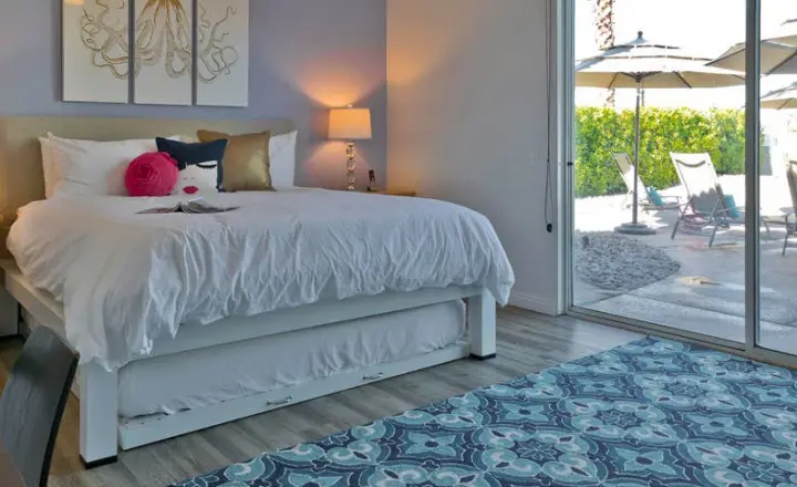 A white King size Platform Bed with a trundle under the bed frame in the master bedroom of a high-end vacation rental in the Coachella Valley.