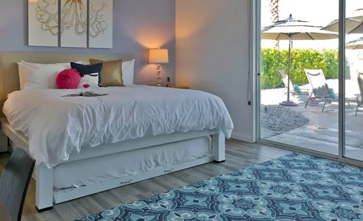 A white King size Platform Bed with a trundle under the bed frame in the master bedroom of a high-end vacation rental in the Coachella Valley.