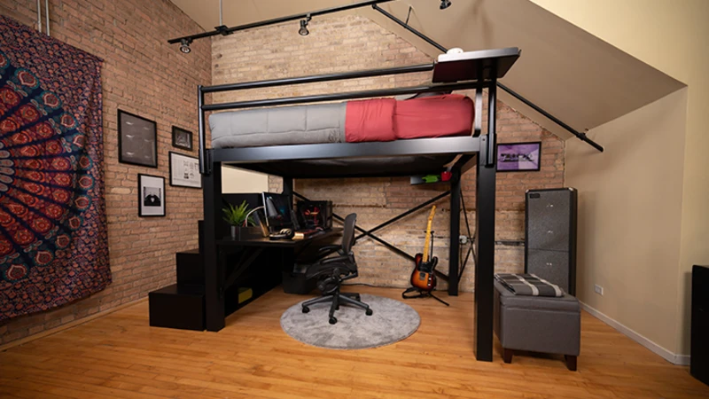 A black queen size Adult Loft Bed with an attached desk under the bed frame with a full PC gaming setup, seen from the left-hand side of the bed at a slight distance.