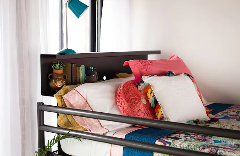 A charcoal Adult Bunk Bed in a fun young adult bedroom decorated with vintage furniture. Seen at a close up of the bookshelf headboard.