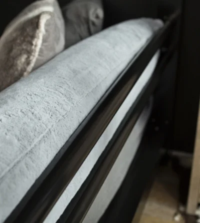 A close up shot on a pillow resting on the bottom bunk PILLOW SUPPORT accessory on a black Queen Over Queen Adult Bunk Bed.