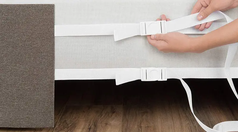 Close up shot of someone tightening the straps on a brown Circa Bed Wrap around a Platform Bed frame.