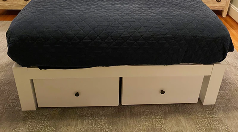 A white queen size platform Standard Bed with two matching metal drawers beneath the bed