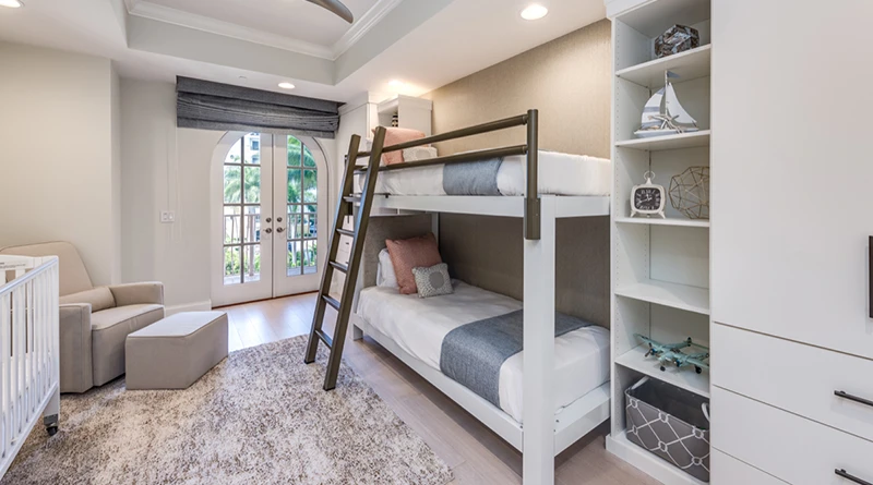 A photo from an interior design magazine of a white Twin XL Over Twin XL Adult Bunk Bed with a light bronze guard rail and light bronze ladder from a vacation home in Naples, Florida.