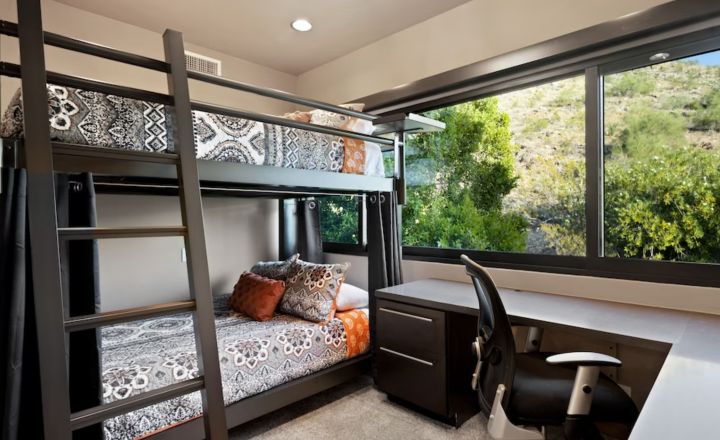 Queen Over Queen Adult Bunk Bed next to a desk in The Happy Roadrunner Phoenix, Arizona vacation property, overlooking a sunny green backyard.