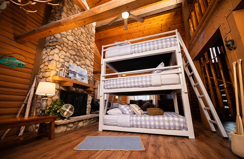 White Triple Bunk Bed for Adults in a classy, upscale cabin seen from a distant low angle facing the right-hand side of the bed with the guardrails.