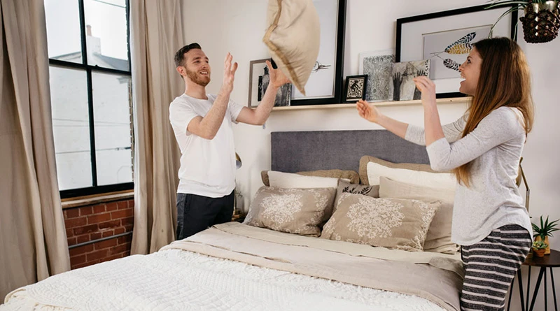 A young couple working together to dress their Queen Standard Bed