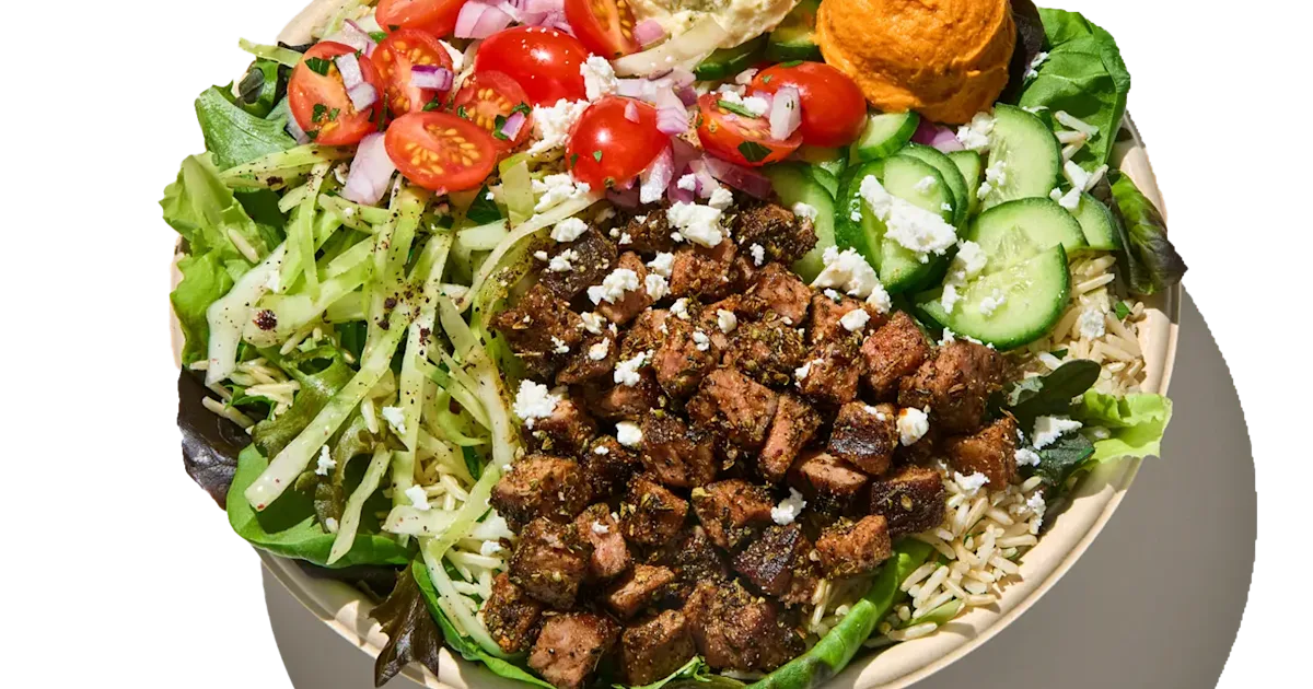 CAVA Steak and Harissa Bowl with grilled steak, rice, greens, dips, vegetables, feta, and vinaigrette