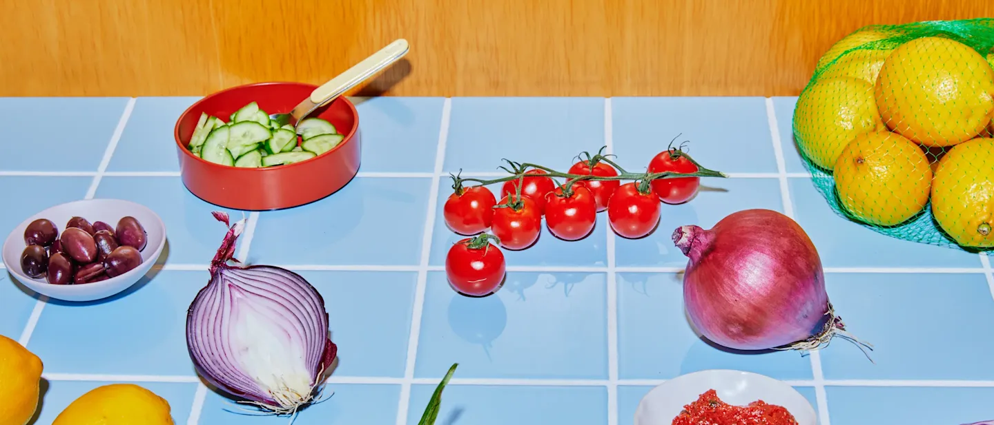 Tomatoes, onions, lemons, and other produce arranged on a surface