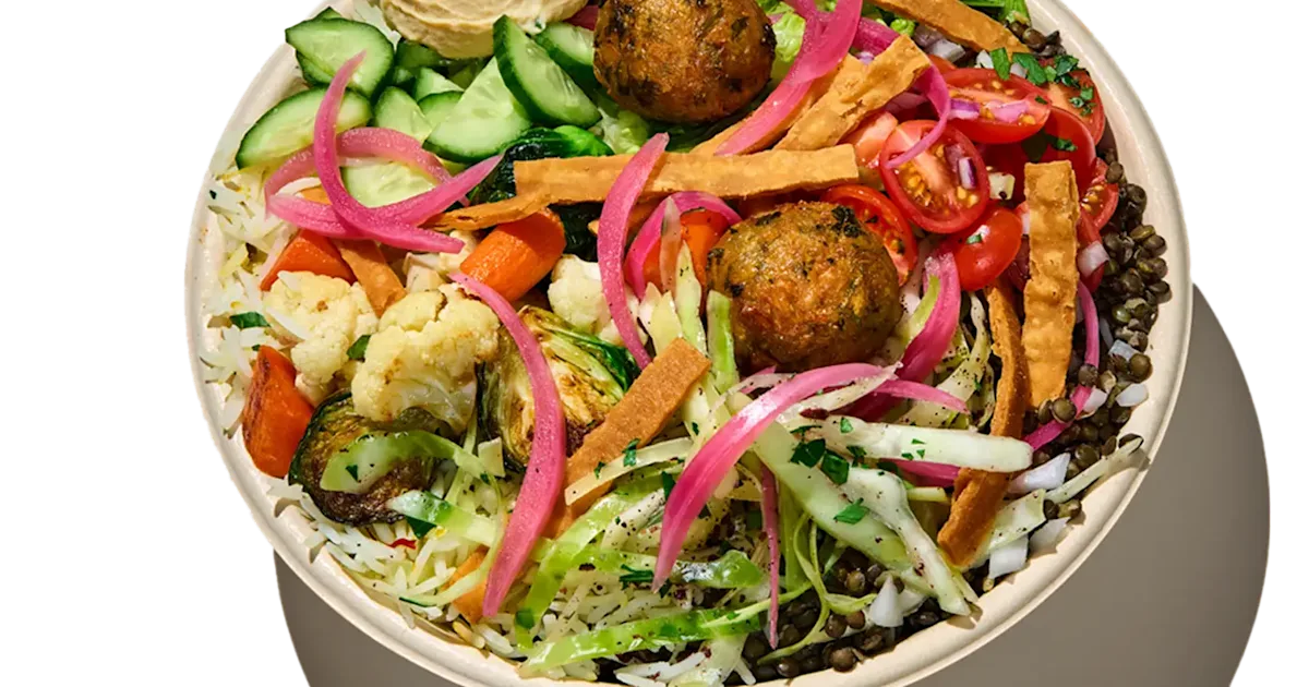 CAVA Falafel Crunch Bowl with falafel, vegetables, dips, greens, rice, lentils, pita crisps, and skhug