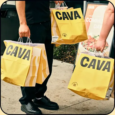 Multiple CAVA bags held outside a restaurant