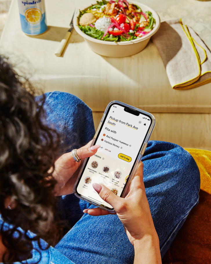 A woman using the CAVA app on her phone to order food