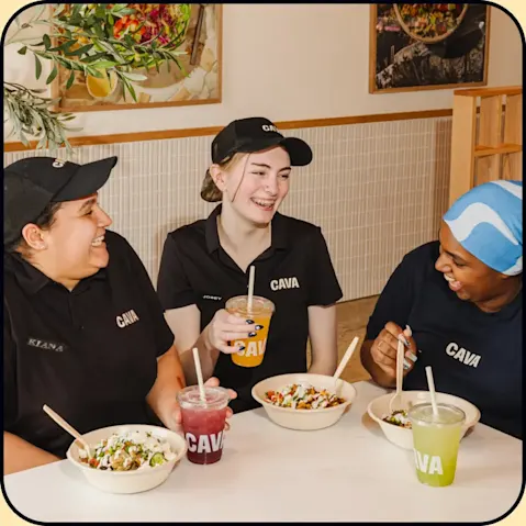 CAVA team members eating CAVA inside a restaurant