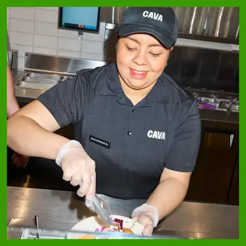 CAVA employee preparing bowl in a restaurant.