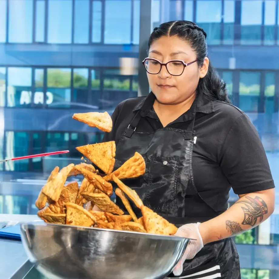 CAVA team member holding a large bowl of pita chips.
