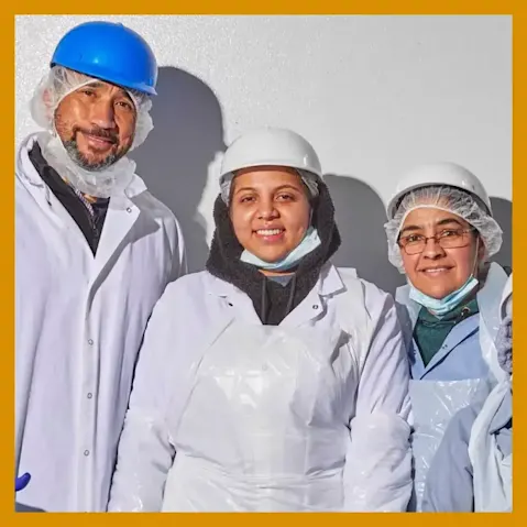 Three manufacturing facility employees wearing protective clothing and hard hats.