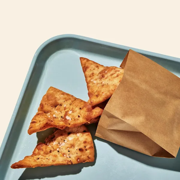 Pita Chips spilling out of a bag onto a blue tray