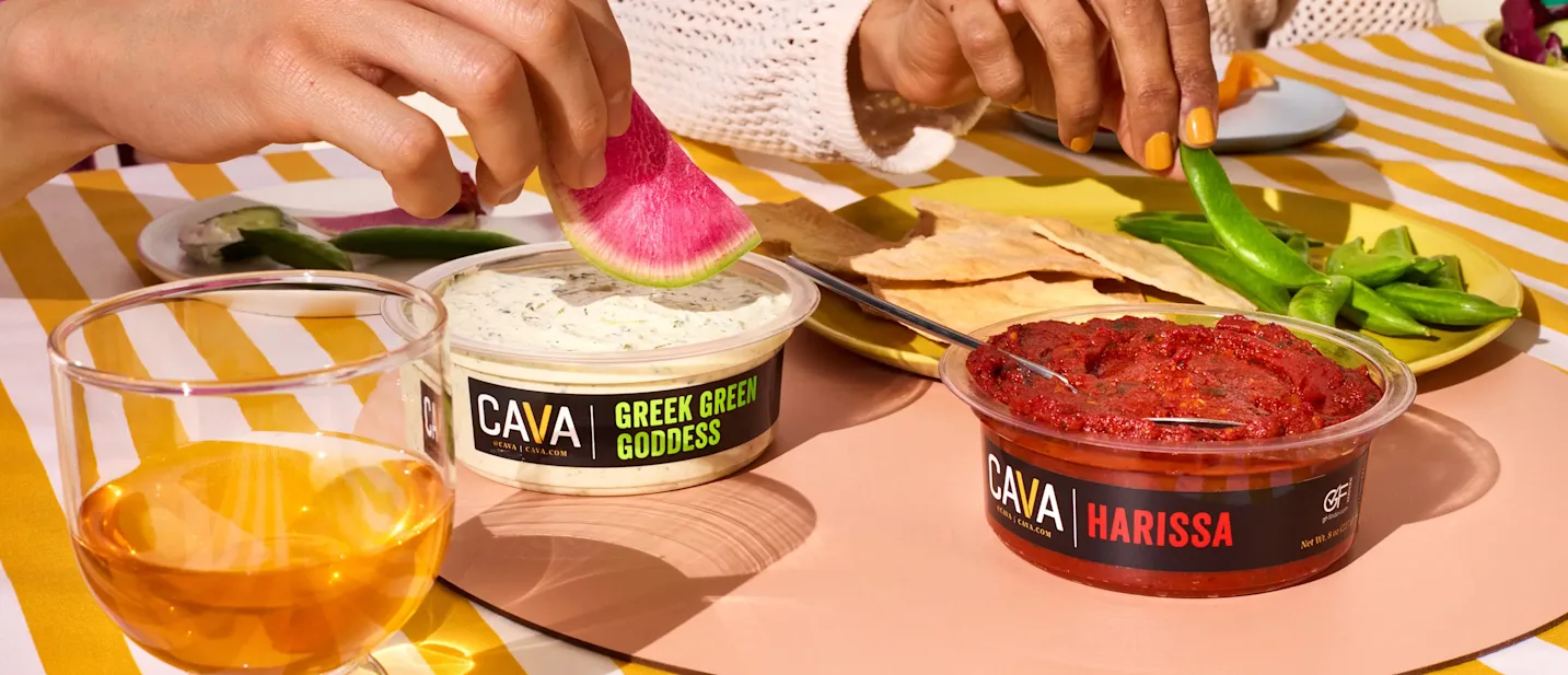 People reaching to dip into CAVA Greek Green Goddess and Harissa dips