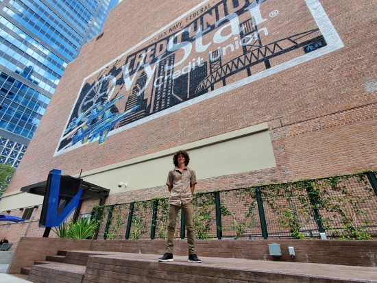 Artist Anthony Rooney standing in front of mural at VyStar Tower