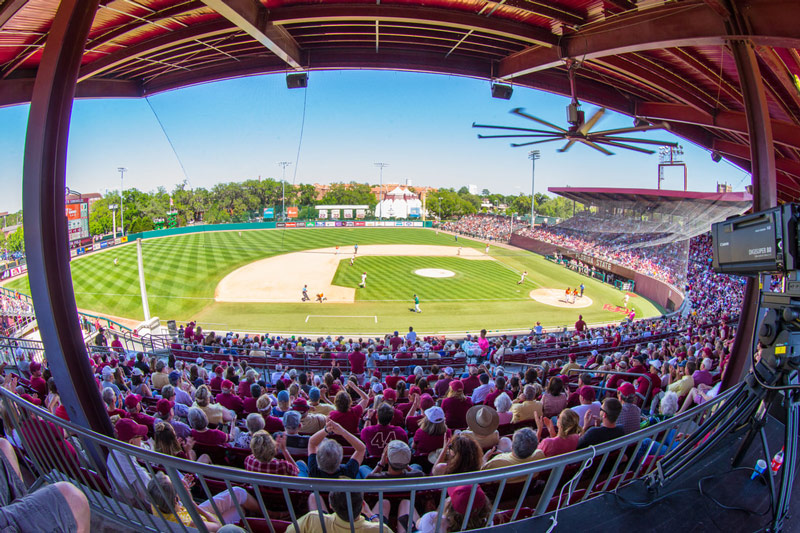 Panoramic view of a baseball game in progress, showing a full crowd in the covered stands and players positioned across the field.