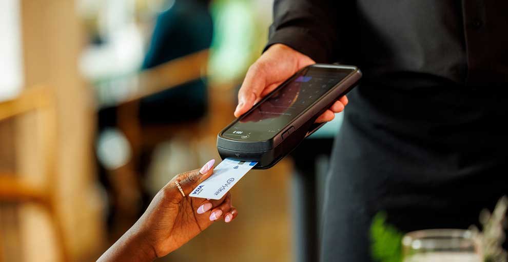 Close up of a hand using a VyStar debit card to make a purchase on a portable point of sale device.
