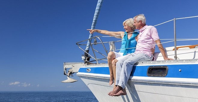A retired couple enjoys a sunny day on a catamaran.