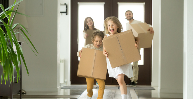 A family carries boxes into their new home.
