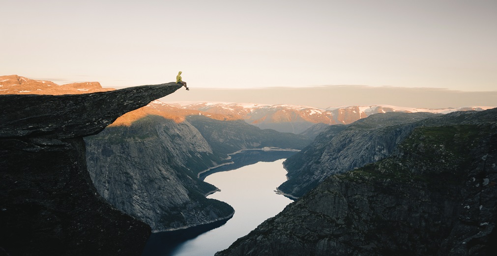 Someone sits on a rock overlooking a river.