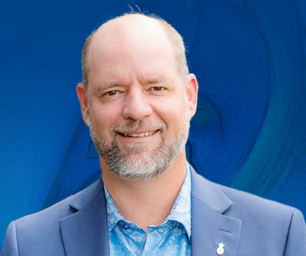 John Compton smiles against a blue background