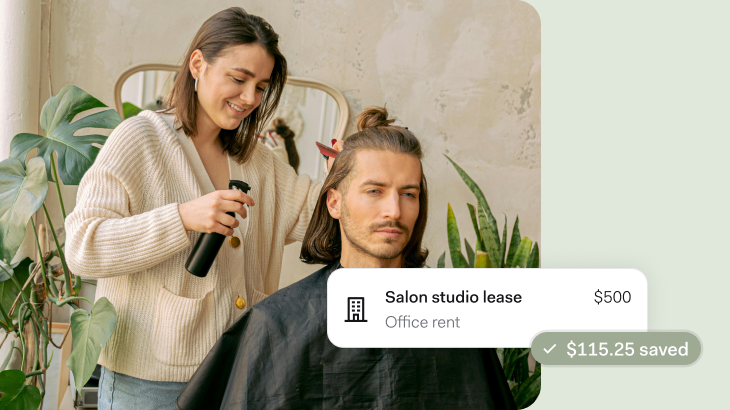 A woman in a cream ribbed cardigan styles a man's shoulder-length hair in a bright, modern salon space with plants and neutral decor. An overlay shows 'Salon studio lease - Office rent $500' with '$115.25 saved' highlighted in green.