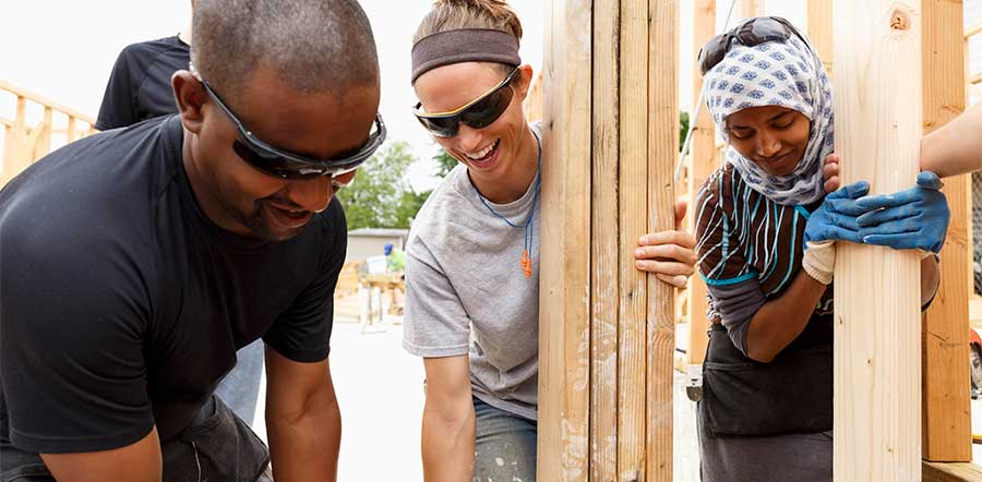 Diverse group of people building a house together