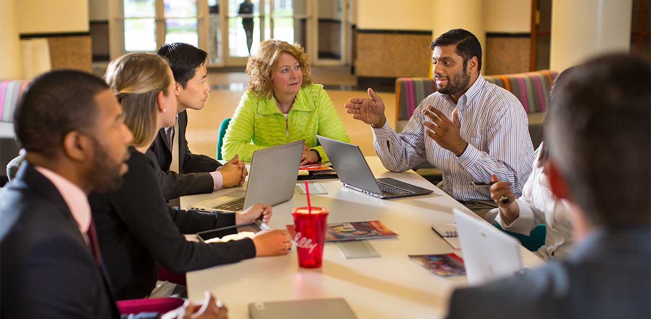 large group of people sitting and talking around a table