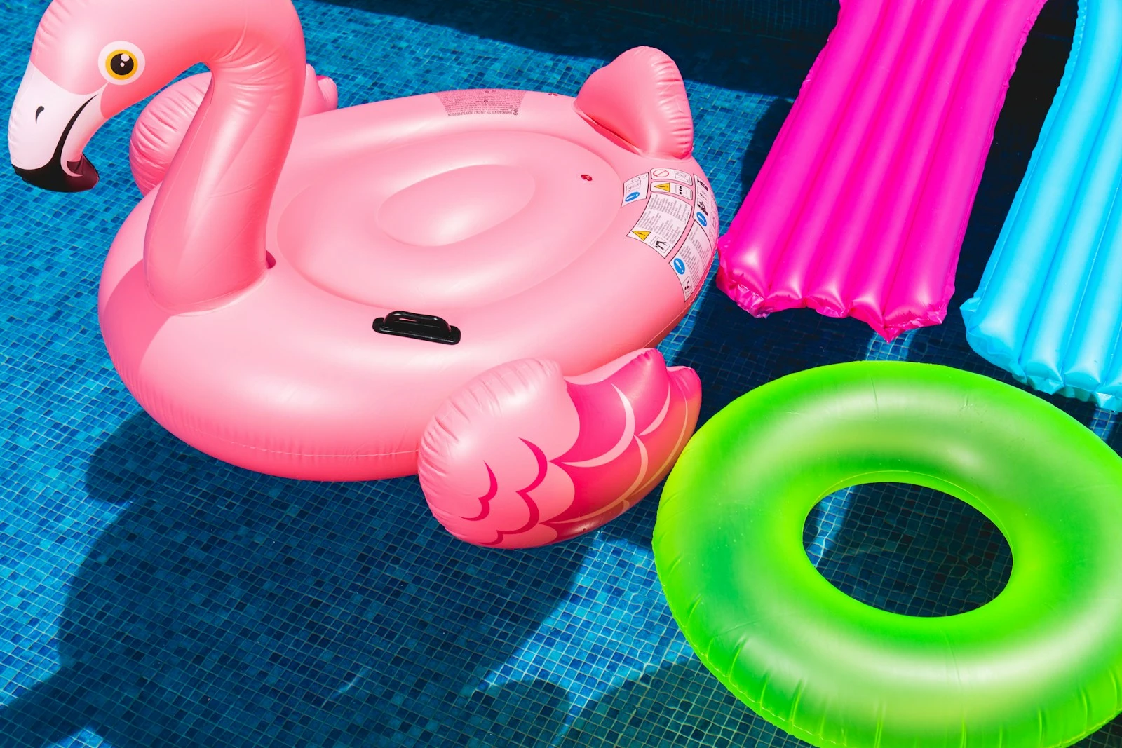 pink inflatable flamingo and green inflatable ring on the water of a pool
