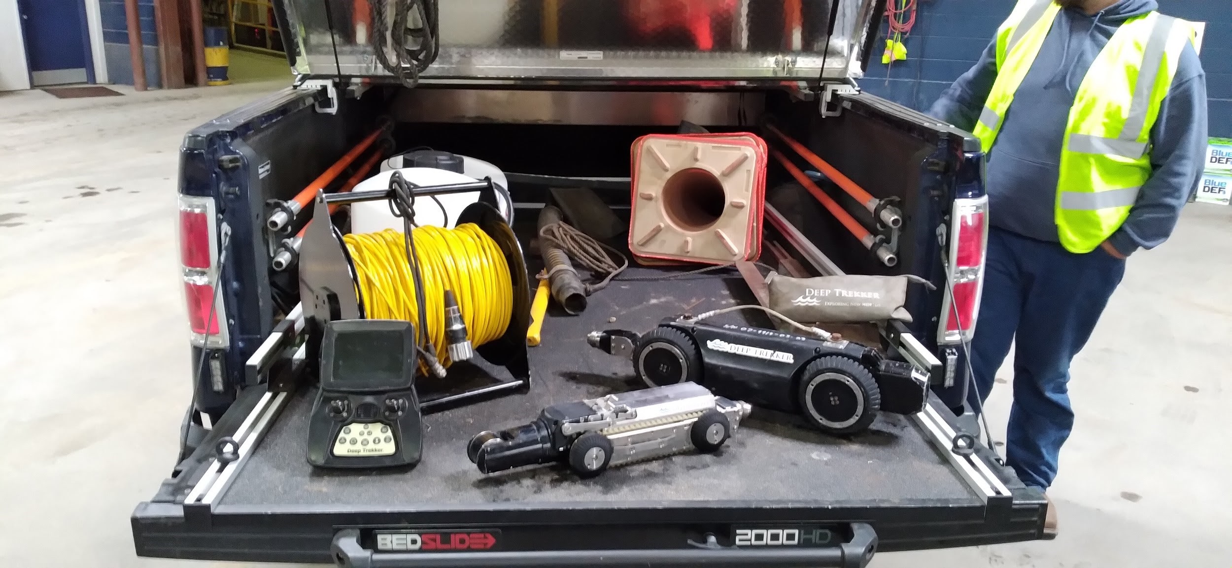 Man standing beside back of pickup truck with Deep Trekker DT340 and DT320 mini pipe crawlers in the back of the truck.