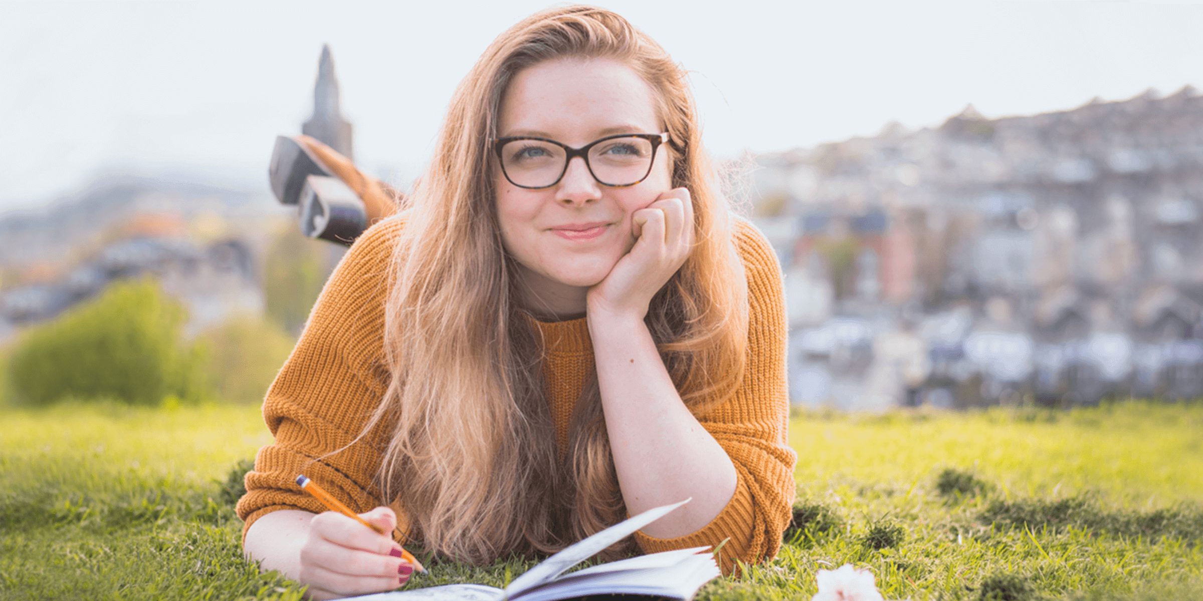 girl laying in the grass writing in her notebook