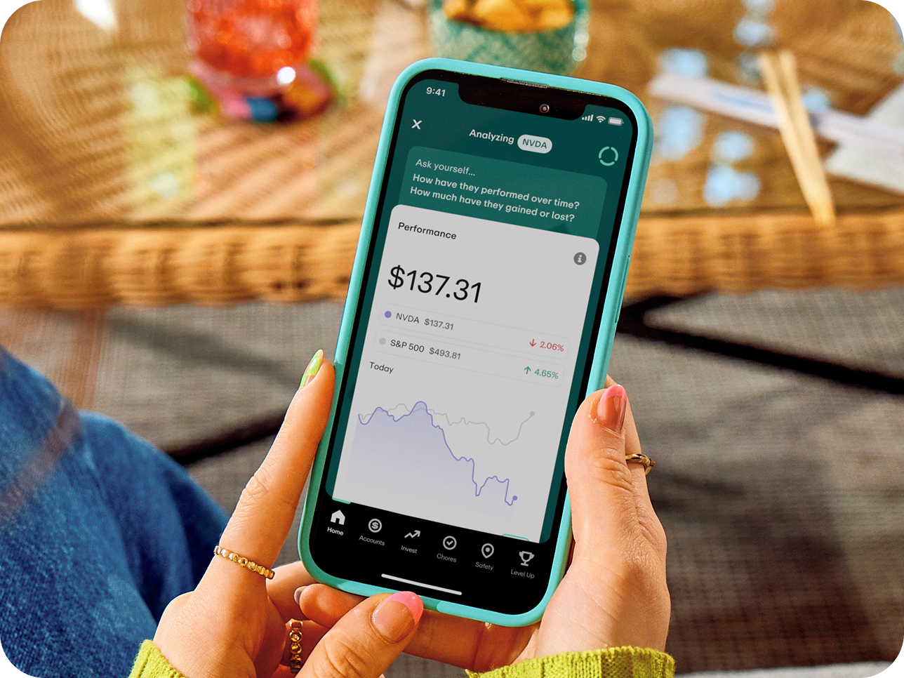 Hands holding teal phone displaying stock performance app showing NVDA at $137.31 and S&P 500 data with performance graph.