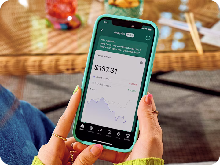 Hands holding teal phone displaying stock performance app showing NVDA at $137.31 and S&P 500 data with performance graph.