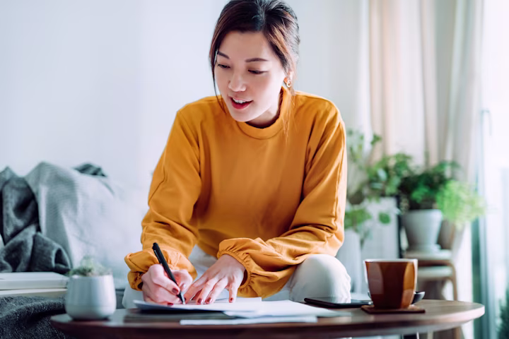 Young adult woman filling out a loan application in her living room. Blog: What is a loan?