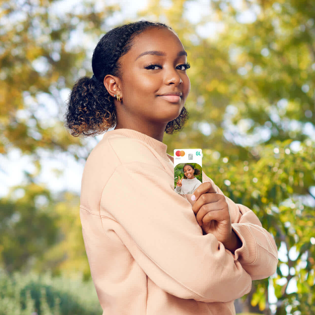teenage girl outside holding a greenlight custom debit card
