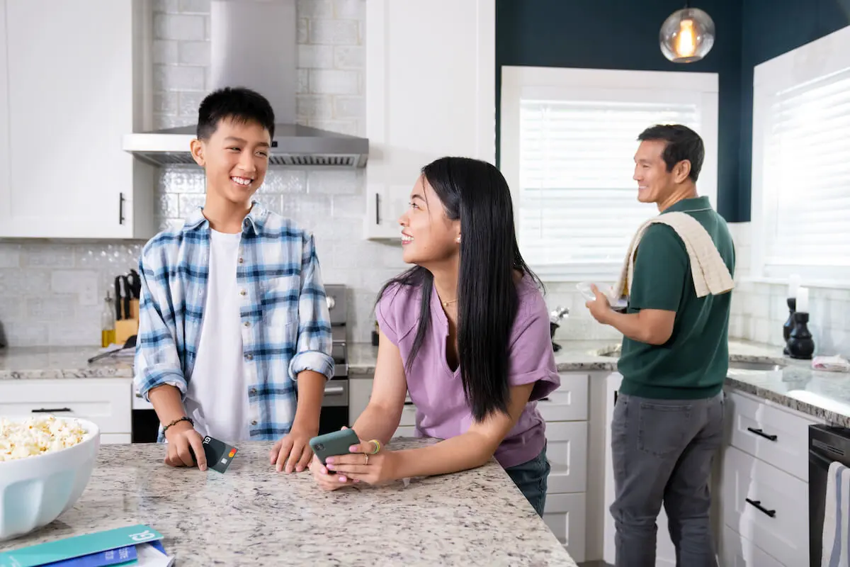 Siblings holding a phone and a credit card