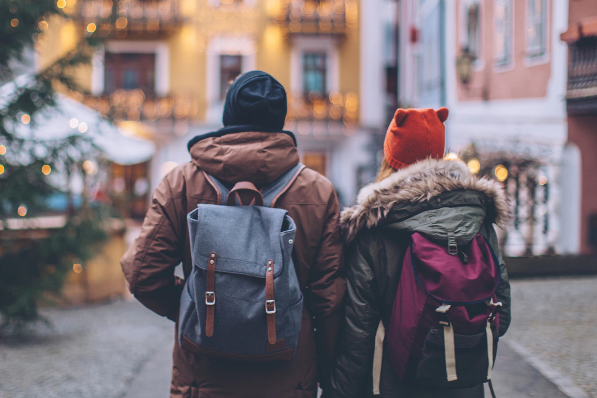 Couple traveling safely through a new town during the holidays - wearing backpacks and winter coats